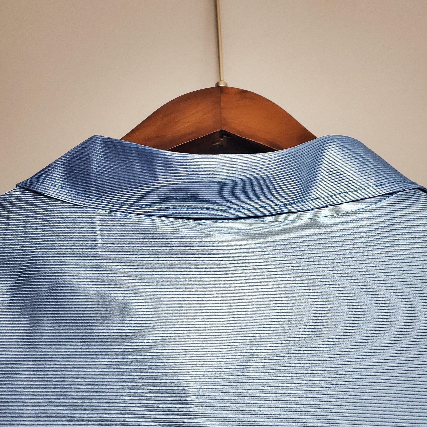 Camisolas Napoli Home 90/91 Retro, detalhe do colarinho em tecido azul, pendurada em cabide.