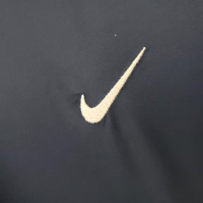 Detalhe do logo Nike em jersey preto, ideal para uso com o PSG Home 02/03 Retro Olympic Store.