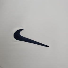 Logo da Nike em um fundo branco, detalhe do design do PSG Away 02/03 Retro branco off.