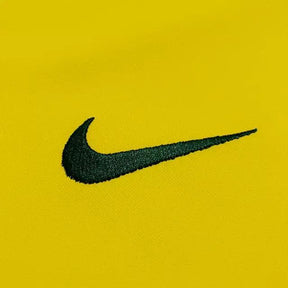 Logo da Nike em bordado preto sobre fundo amarelo da Camisola Brasil Home 1998 Retrô.