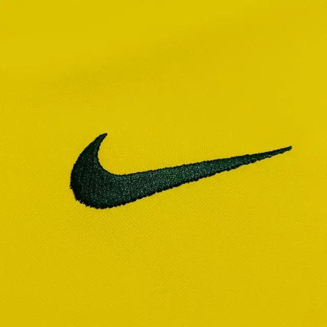 Logo da Nike em bordado preto sobre fundo amarelo da Camisola Brasil Home 1998 Retrô.