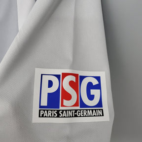 Logotipo do Paris Saint-Germain em camisola retro PSG Away 01/02 branca, estilo clássico e elegante.