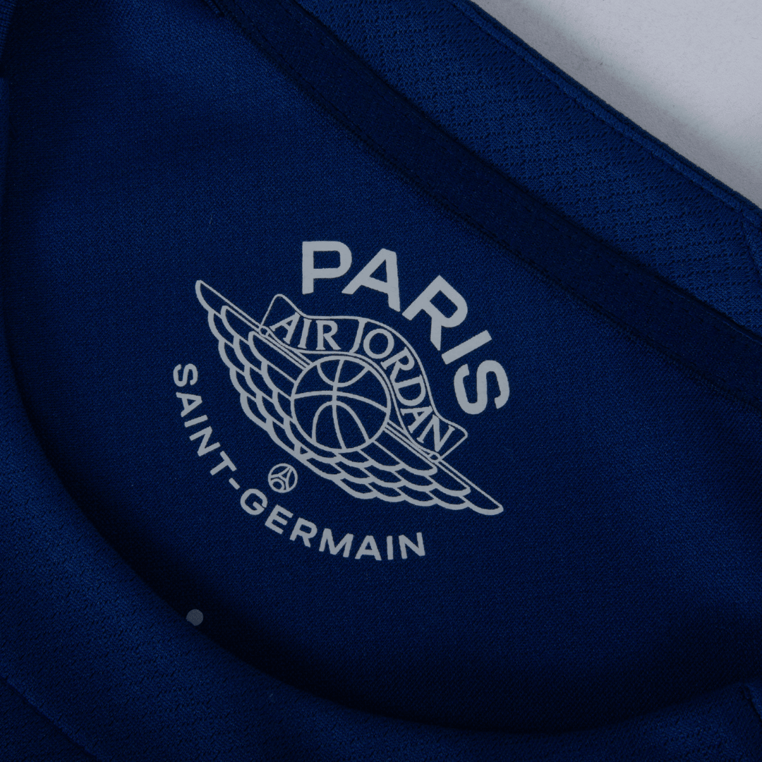 Logotipo da camiseta PSG fourth 24/25 azul marinho com Air Jordan e Paris Saint-Germain.