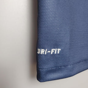Detalhe da camisola PSG Home 12/13 Retro Azul Marinho, mostrando a tecnologia DRI-FIT para conforto e desempenho.