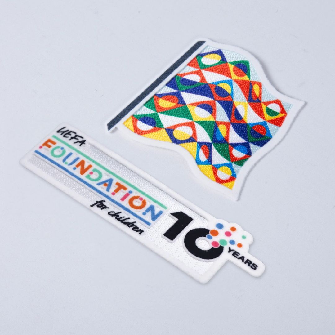 Logos comemorativos do 10º aniversário da UEFA Foundation for Children e bandeira colorida.